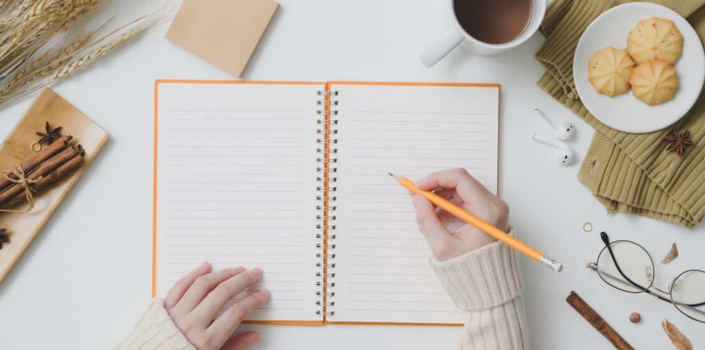 person preparing to write in notebook with pencil